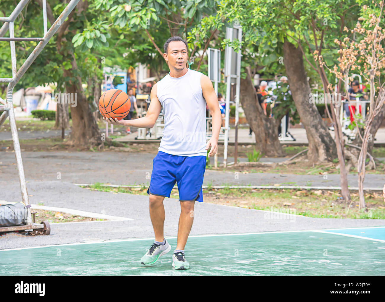Le basket-ball dans la main de l'homme asiatique à exercer à l'arbre de fond Bang Yai Park , Nonthaburi en Thaïlande. Banque D'Images