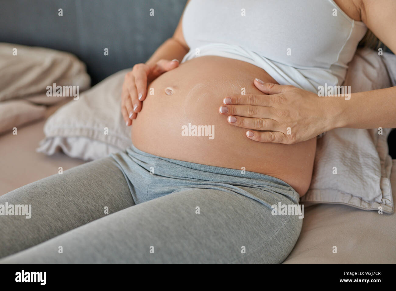 Jeune femme enceinte se frotter la crème hydratante sur son ventre pour hydrater sa peau et réduire le risque de vergetures après l'accouchement Banque D'Images
