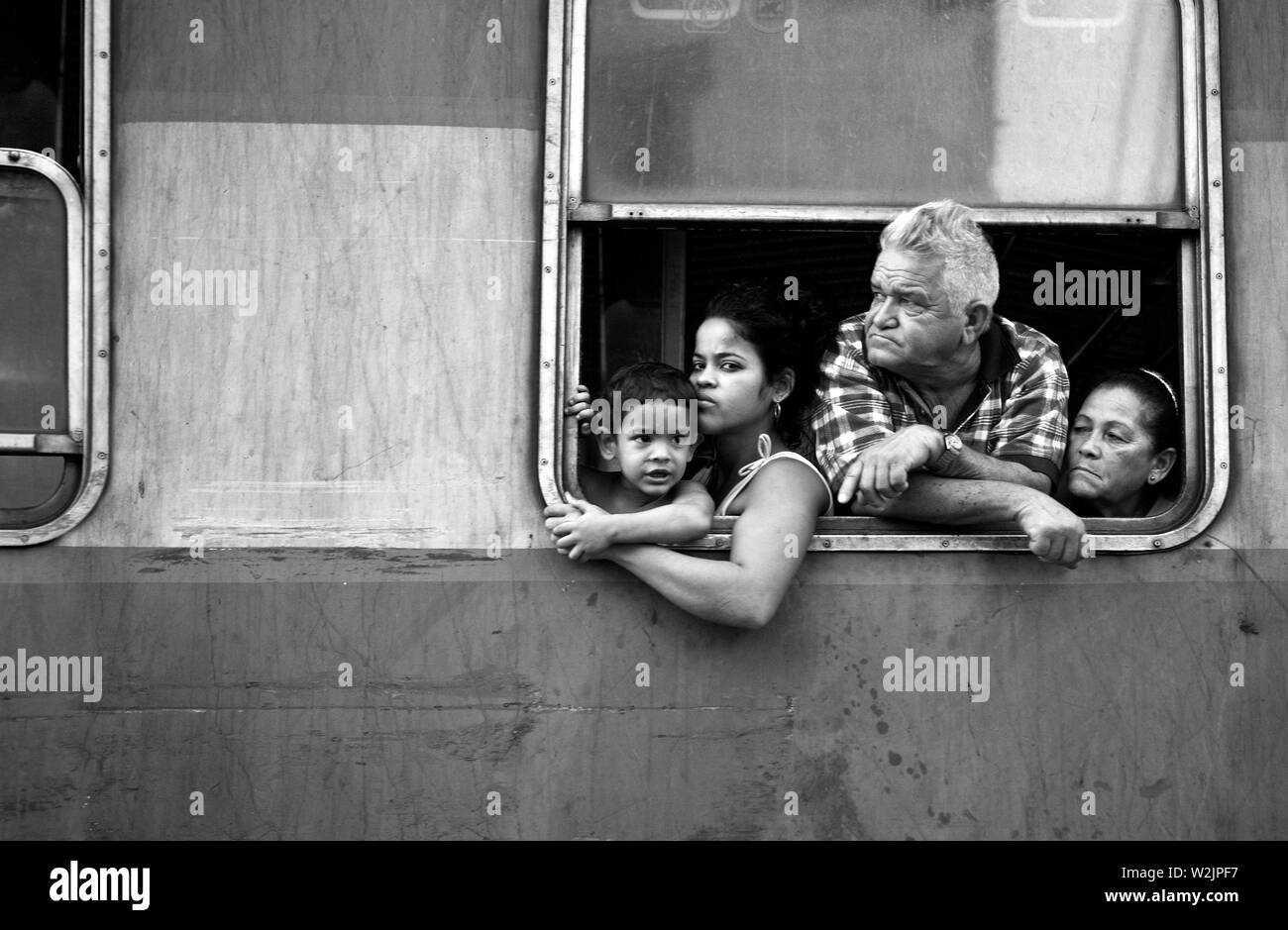 Cette famille regarde la ville de Camacey alors que leur train ralentit à l'approche des routes qui traversent les voies. Banque D'Images