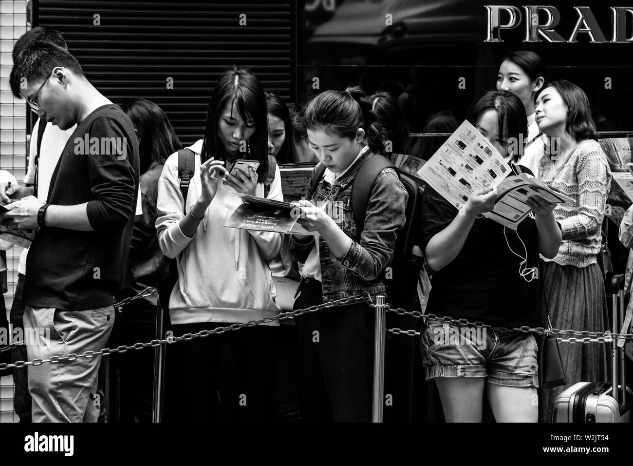 Les jeunes gens riches de Hong Kong d'attente à l'extérieur d'une boutique à Causeway Bay, Hong Kong, Chine Banque D'Images
