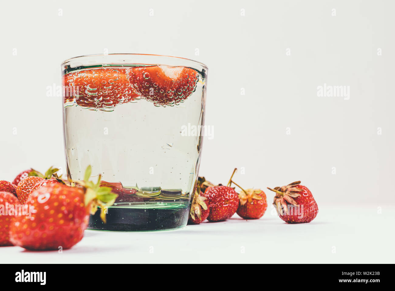 L'eau de soude infusé avec des fraises à côté de fruits mûrs sur tableau blanc, close-up. Banque D'Images