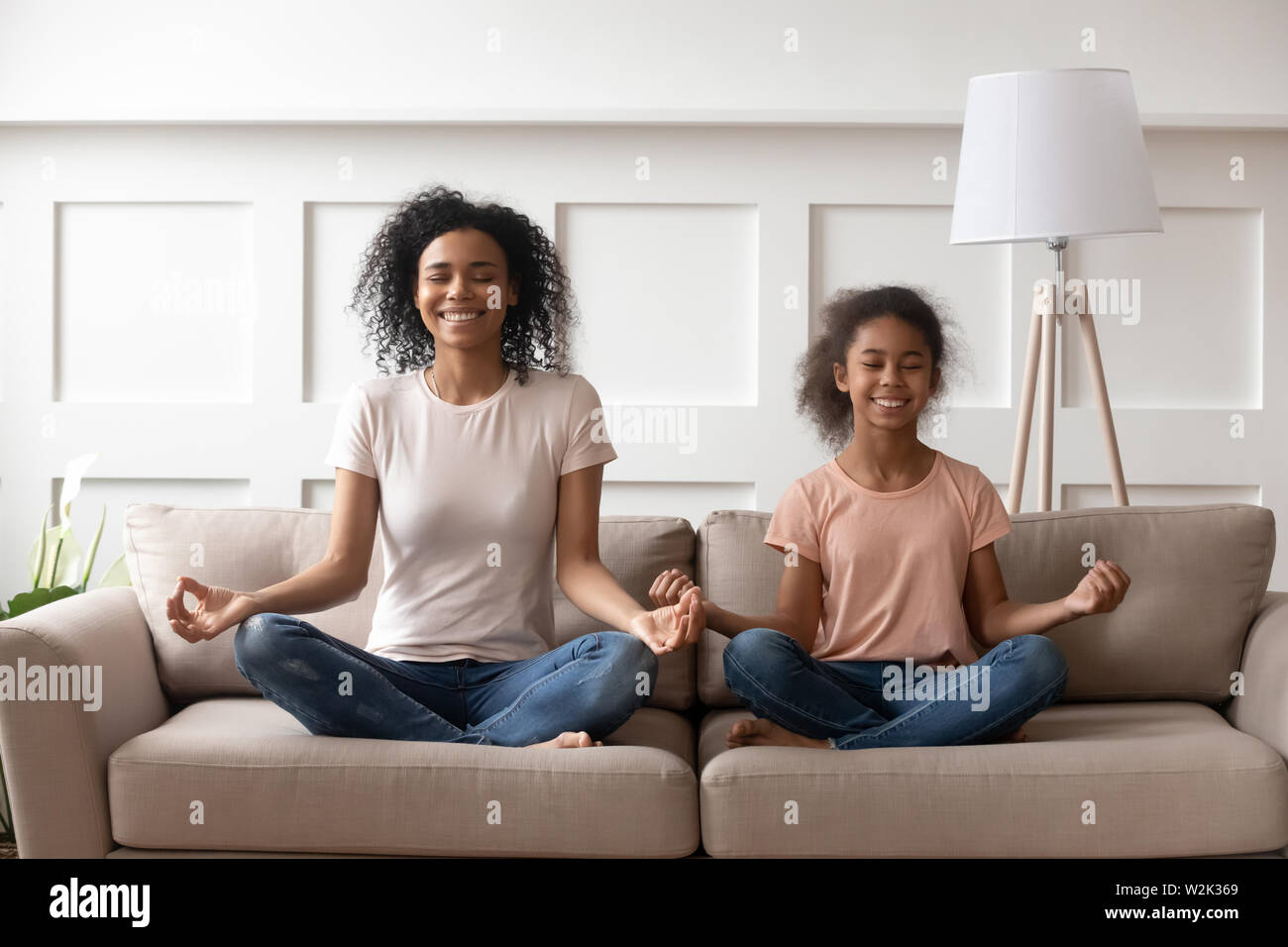 L'enseignement de l'Afrique de l'heureuse maman kid fille faisant du yoga à la maison Banque D'Images