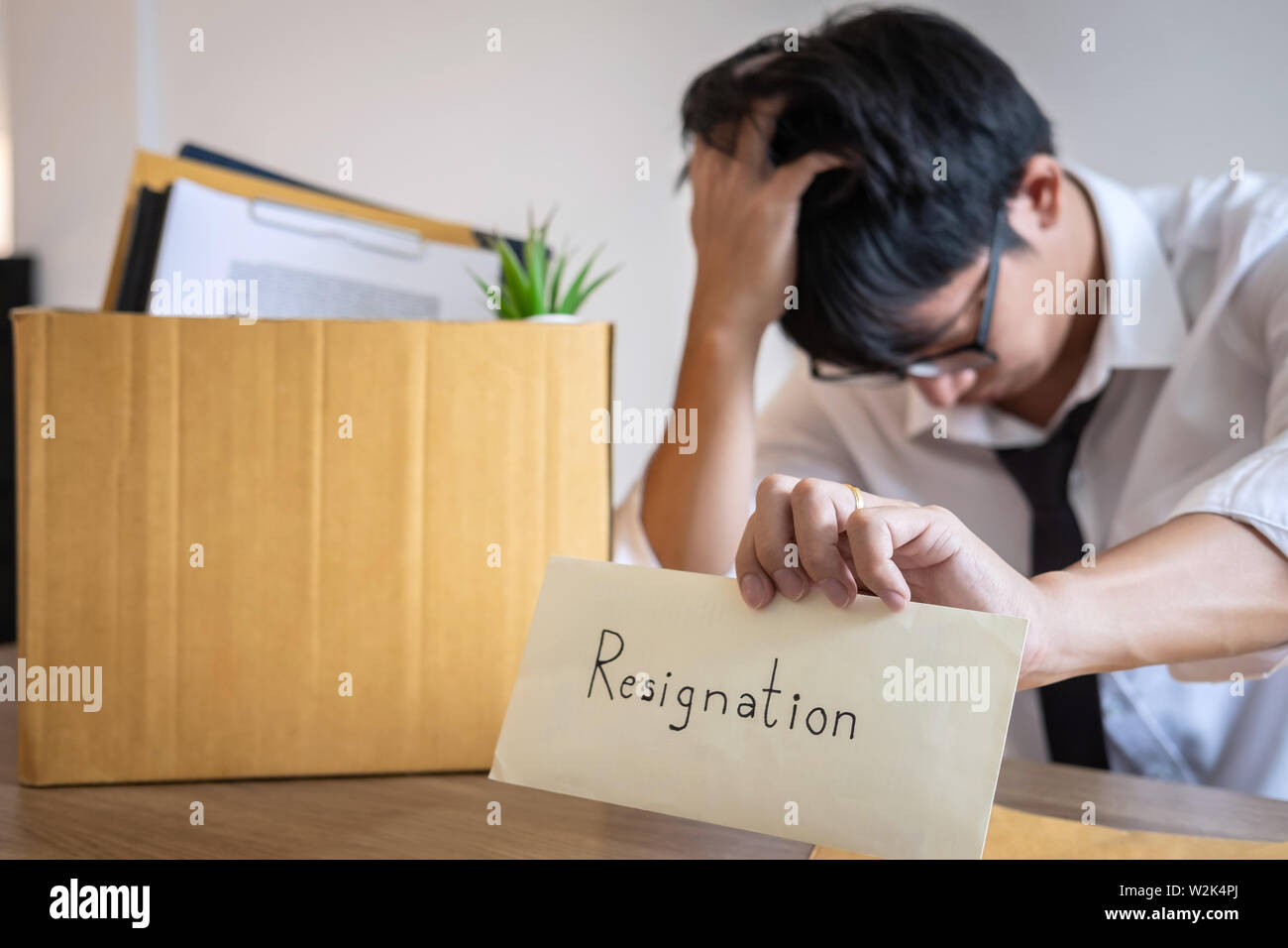 Stressed businessman va être démission et effets personnels d'emballage société et fichiers dans boîte en carton brun, changeant et démissionnera de travail conceptuel Banque D'Images