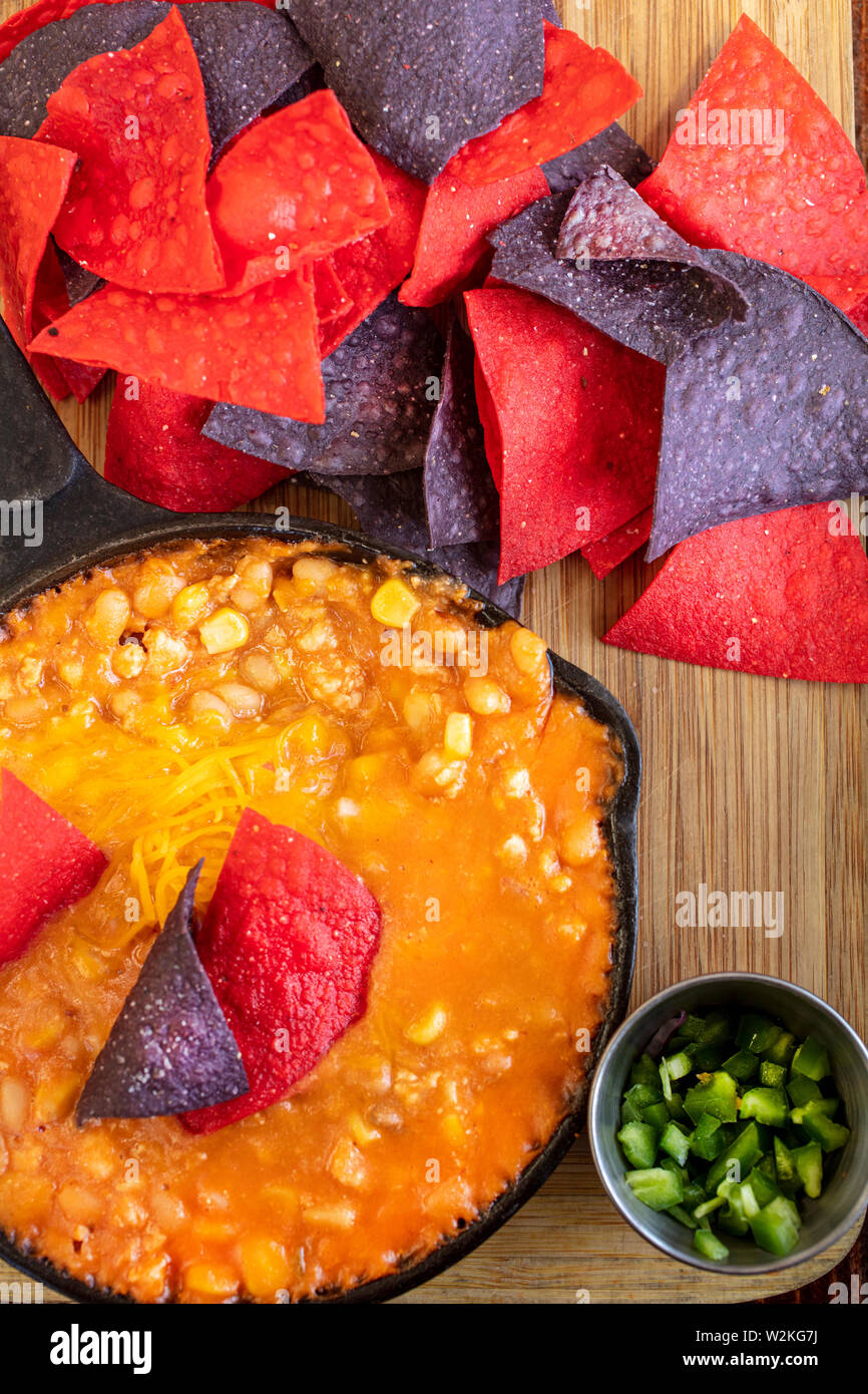 Poulet mexicain Chili faite avec du maïs et des haricots dans un poêlon en fonte, avec le rouge et le bleu des croustilles tortillas et piments jalapenos Banque D'Images