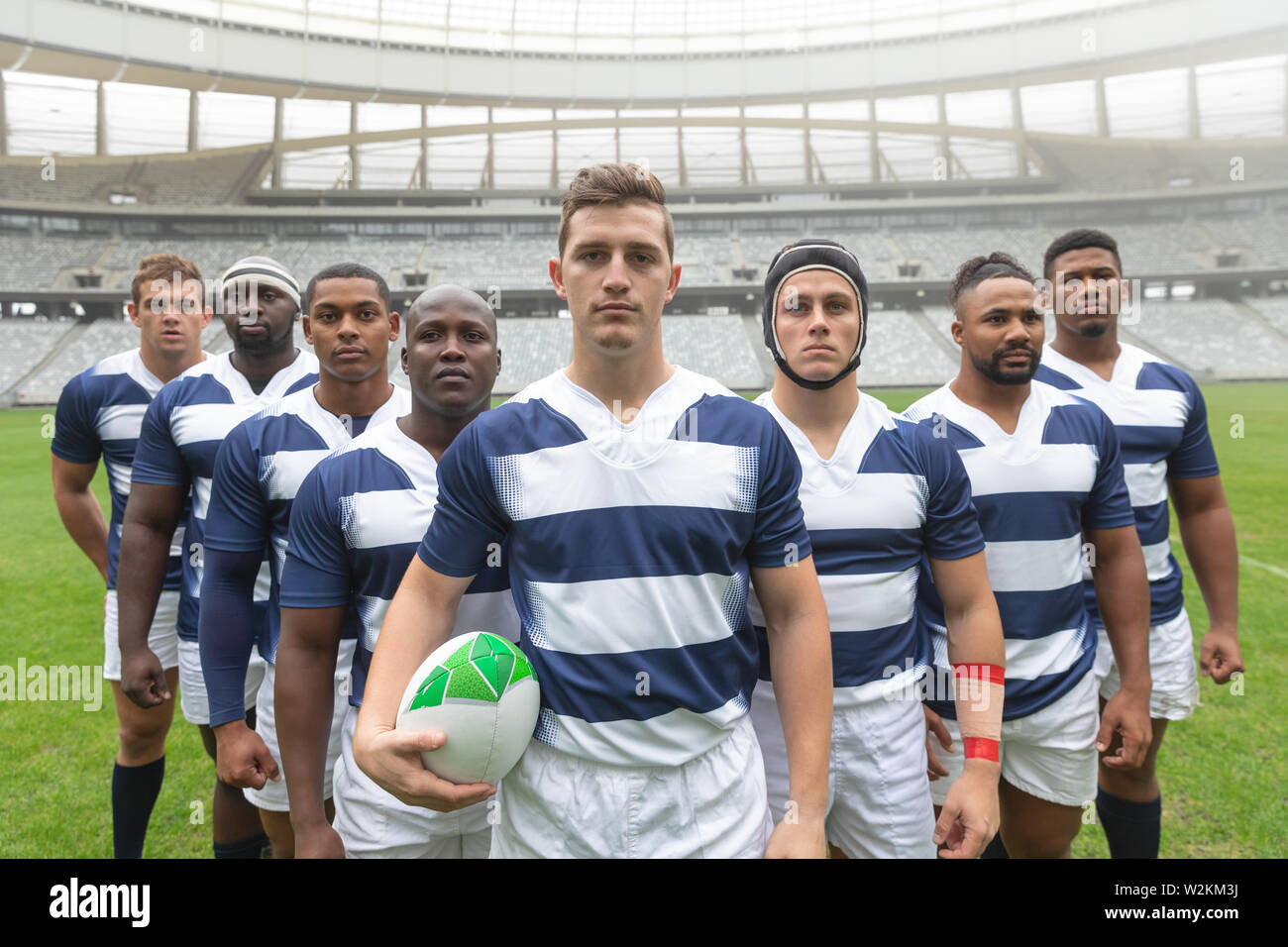 Groupe de divers joueurs de rugby masculin debout avec ballon de rugby au stadium Banque D'Images