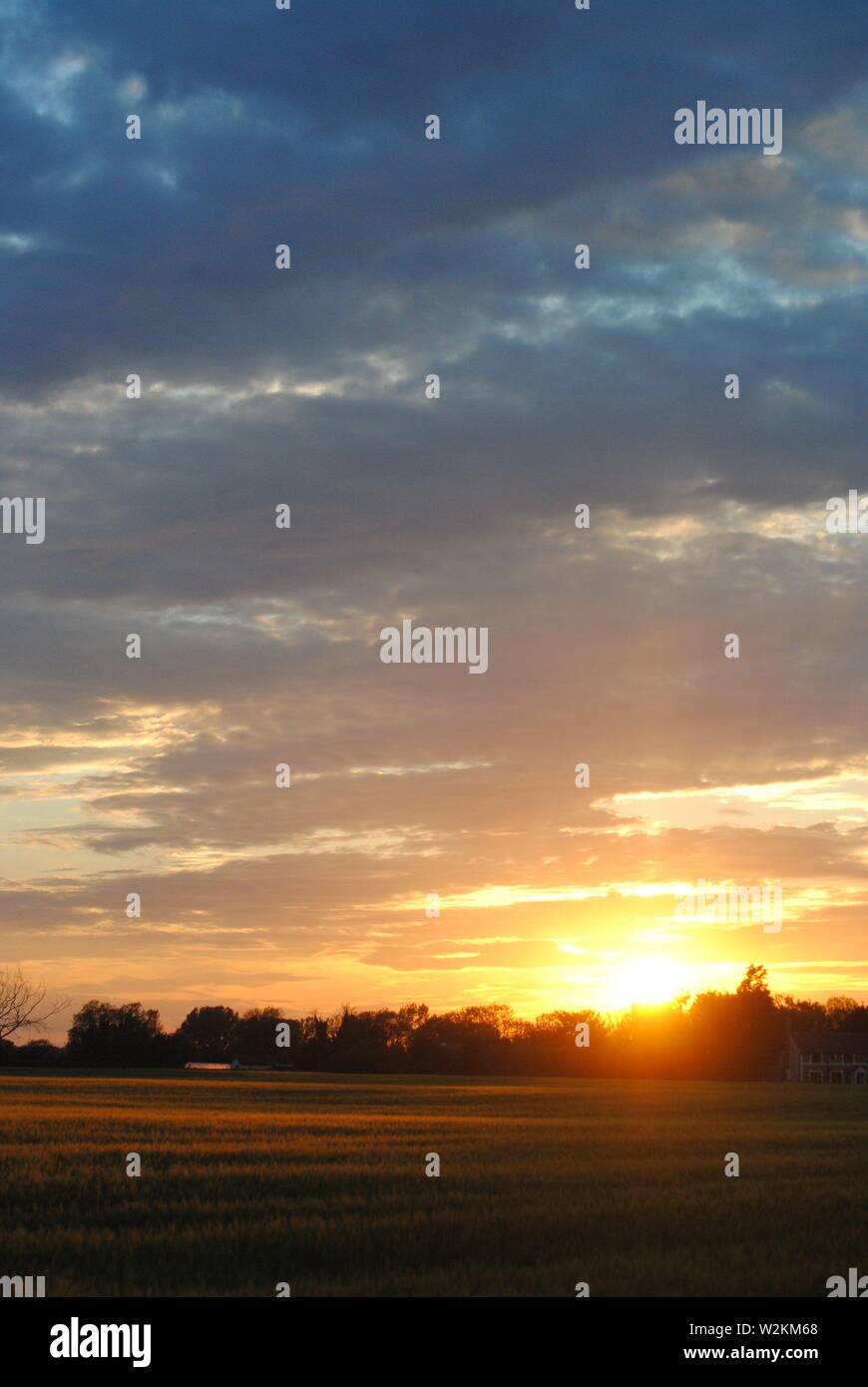 Coucher de soleil sur les champs de Suffolk, été orange jaune soleil avec des nuages sombres Banque D'Images