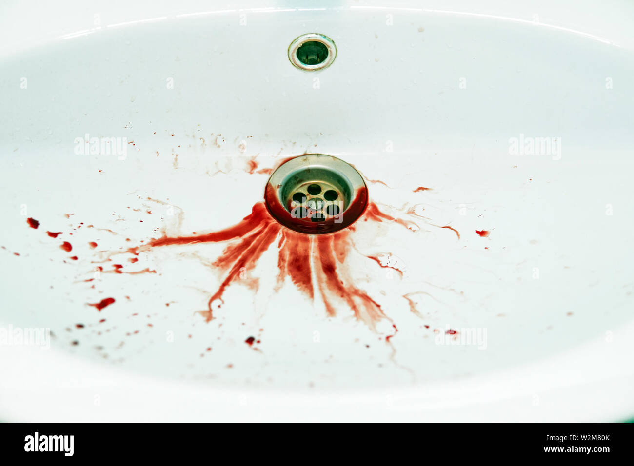 Les inondations de sang rouge dripple à la vidange lavabo blanc. Salle de bains lavabo est souillée de taches de sang. État défectueux. Des saignements a spitted dans Banque D'Images