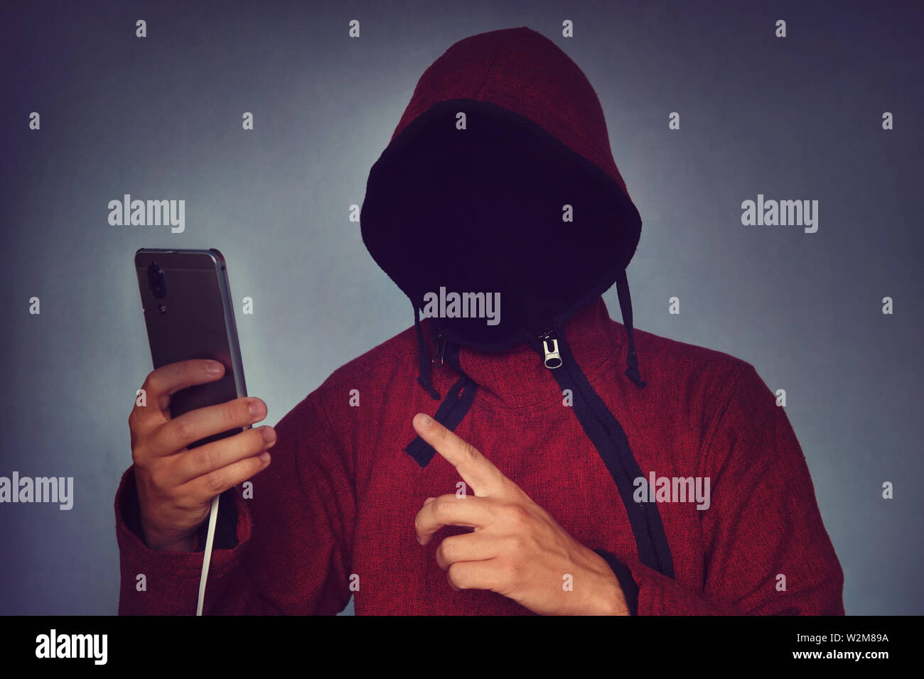 Personne à capuchon sans visage méconnaissable à l'aide de téléphone mobile, le vol d'identité et le crime de la technologie concept, selective focus on corps. hacking un smartphone Banque D'Images