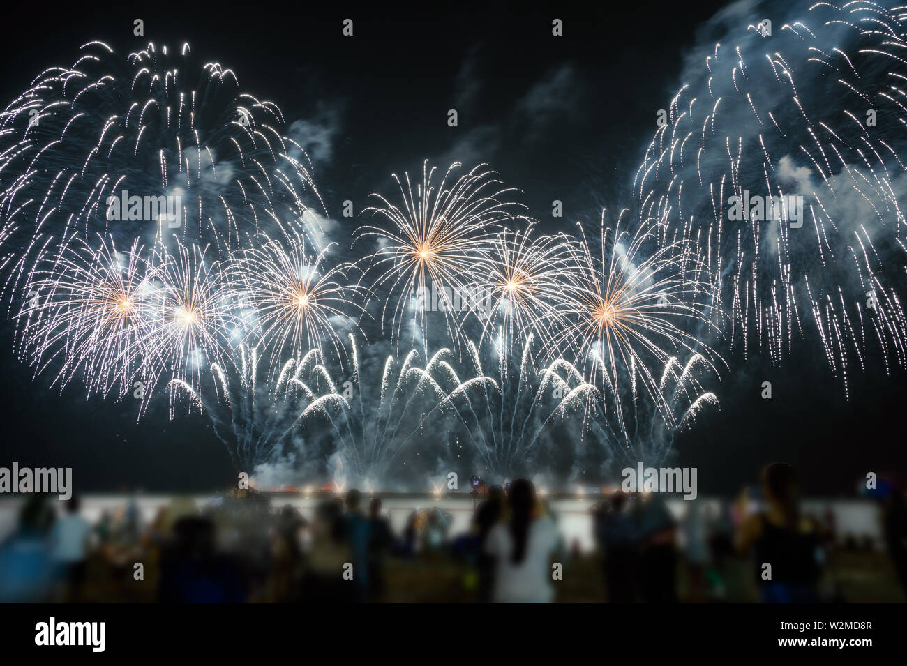 Les spectateurs regardent d'artifice de couleurs dans le ciel de nuit sur la plage de fête annuelle Banque D'Images