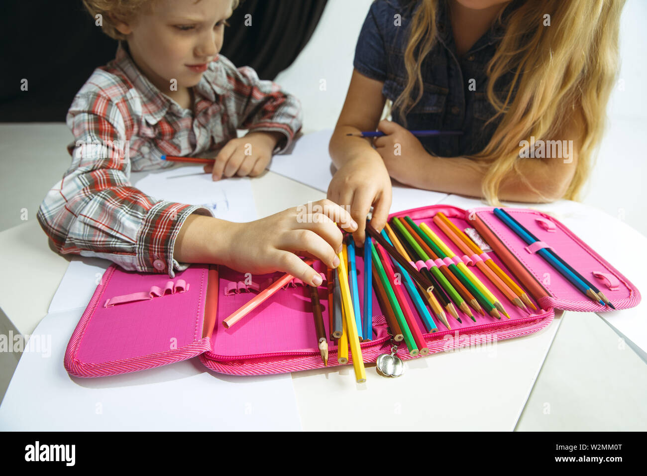 Garçon et fille se préparer à l'école après une longue pause de l'été. Retour à l'école. Peu de modèles de race blanche dimensions ensemble sur fond noir et blanc. L'enfance, l'éducation, les devoirs de vacances ou concept. Banque D'Images