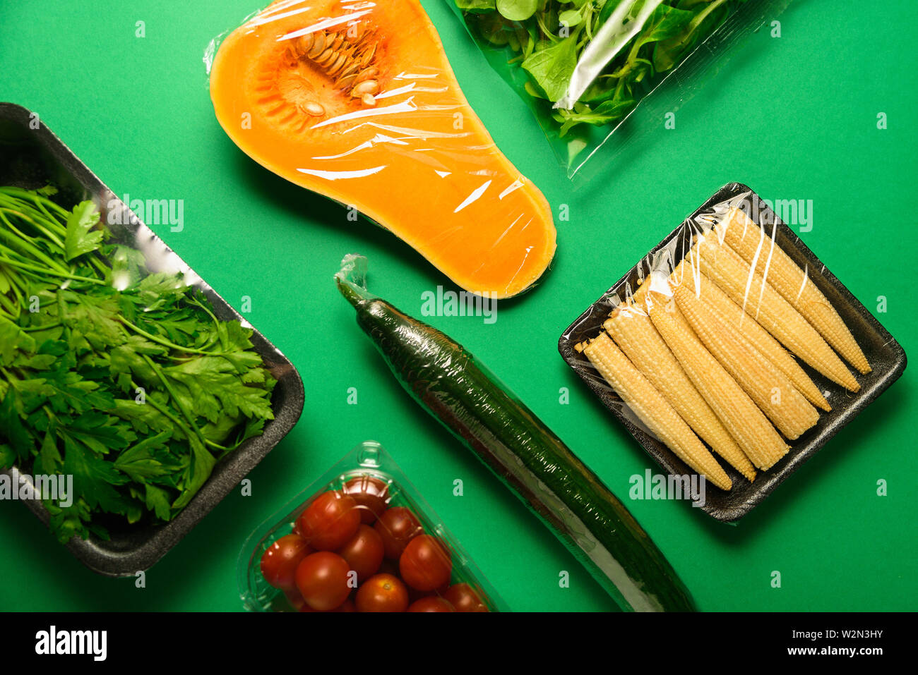 Légumes frais en emballage en plastique. Zéro déchets, recycler concept. La pollution plastique. Fond vert Banque D'Images