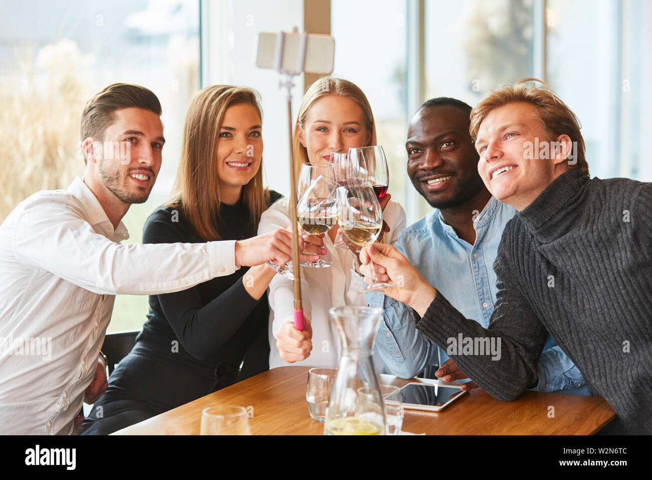 Les jeunes dans le restaurant toast avec du vin et de prendre un des selfies Banque D'Images
