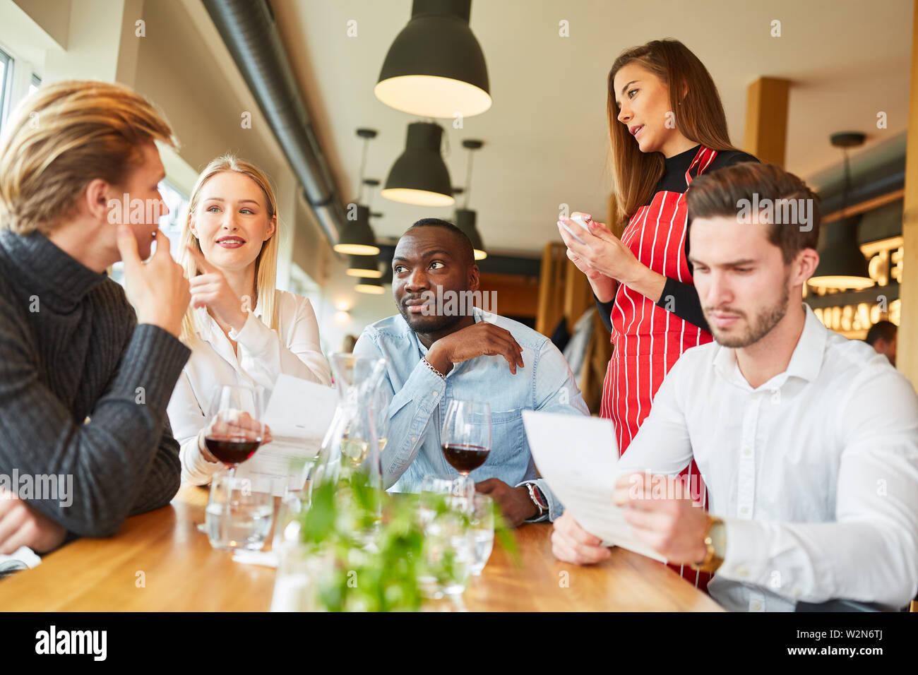Serveuse attend pour commander les jeunes en tant qu'invités dans le bistro ou restaurant Banque D'Images