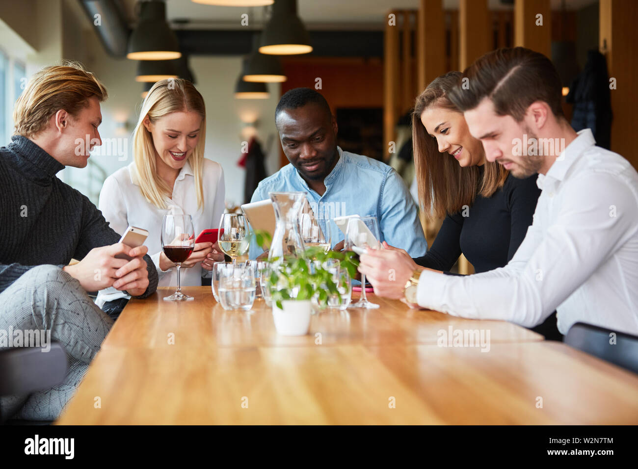 Les jeunes dans le restaurant sont constamment à la recherche de leur téléphone intelligent ou mobile Banque D'Images