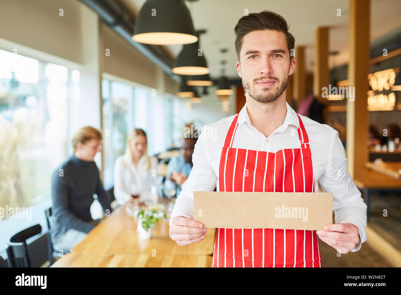 Serveur détient dans le restaurant vide pancarte dans ses mains Banque D'Images