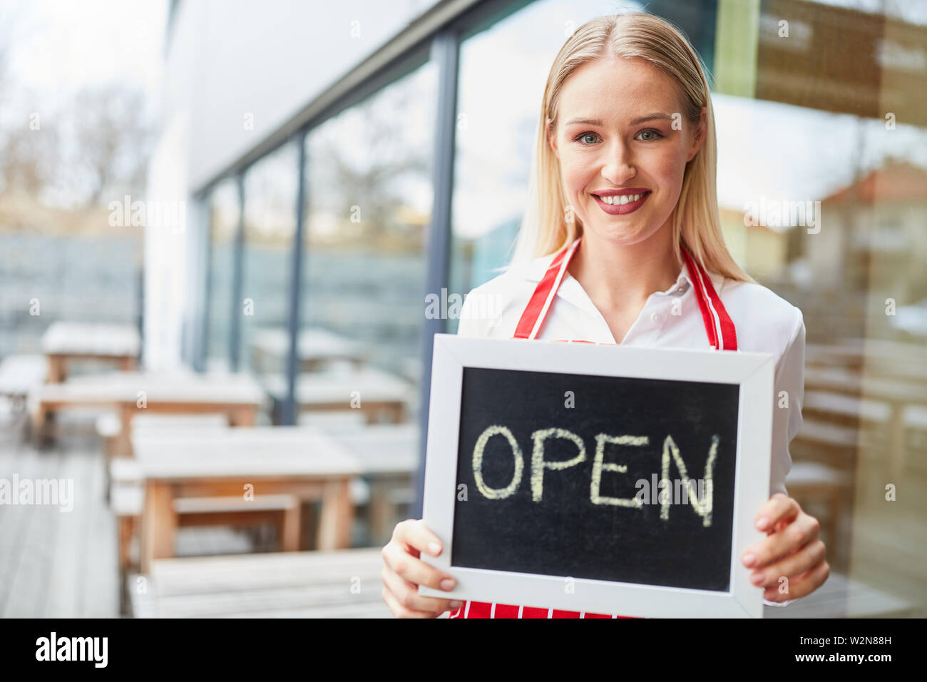 Jeune femme en tant que serveuse brandissait une déficience en face de restaurant ou bistro Banque D'Images Jeune femme en tant que serveuse brandissait une déficience en face de restaurant ou bistro Banque D'Images
