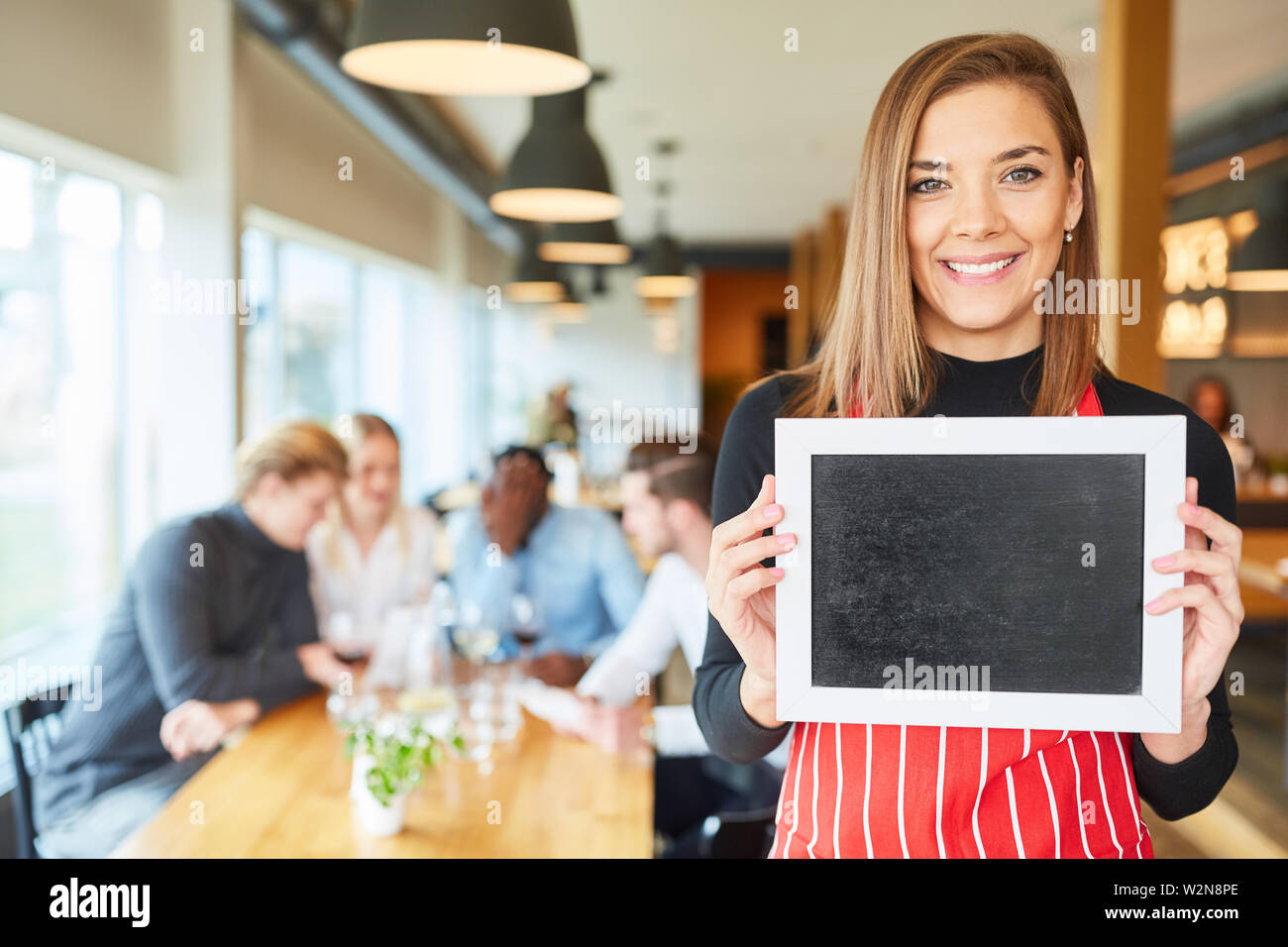 Jeune serveuse ou serveuse est holding a blank tableau dans le restaurant Banque D'Images