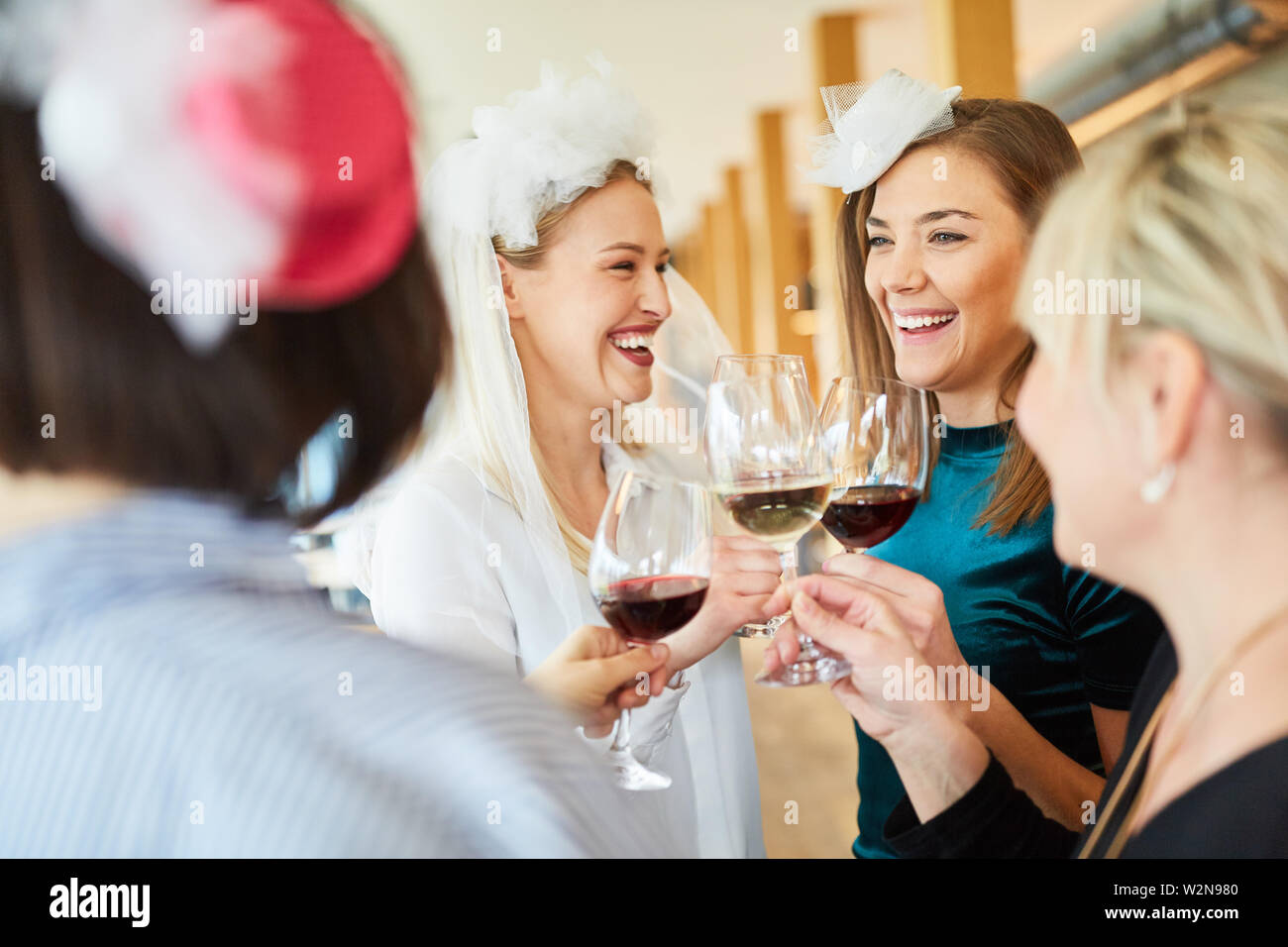 Les femmes boire un verre de vin rouge avec la mariée à hen party Banque D'Images