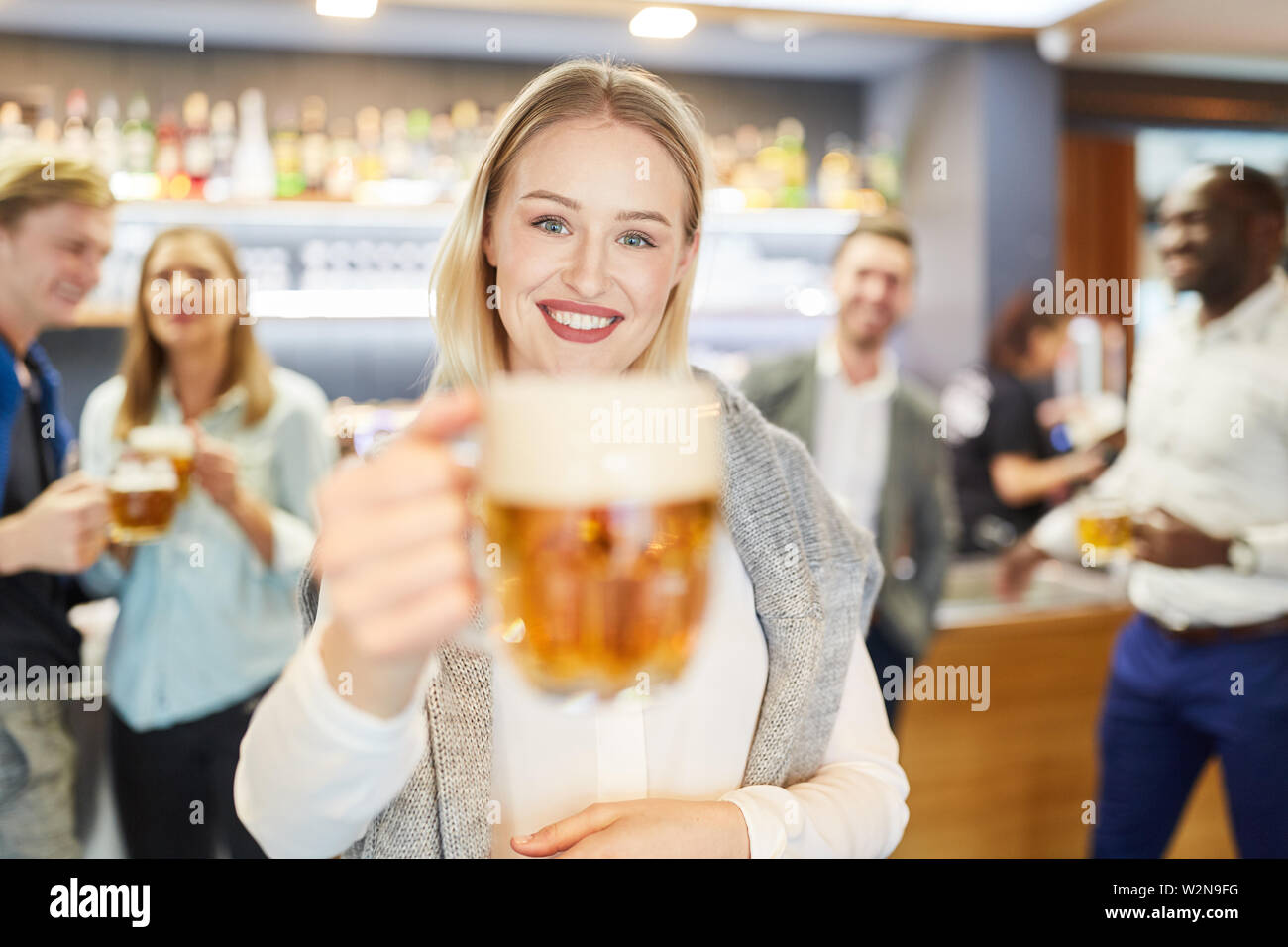 Jeune femme joyeuse dégustation avec un verre de bière dans un pub Banque D'Images