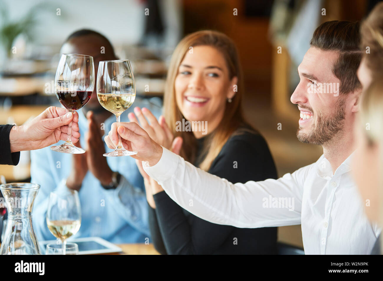 Jeune homme se fête avec des amis dans le restaurant et le grillage avec un verre de vin Banque D'Images