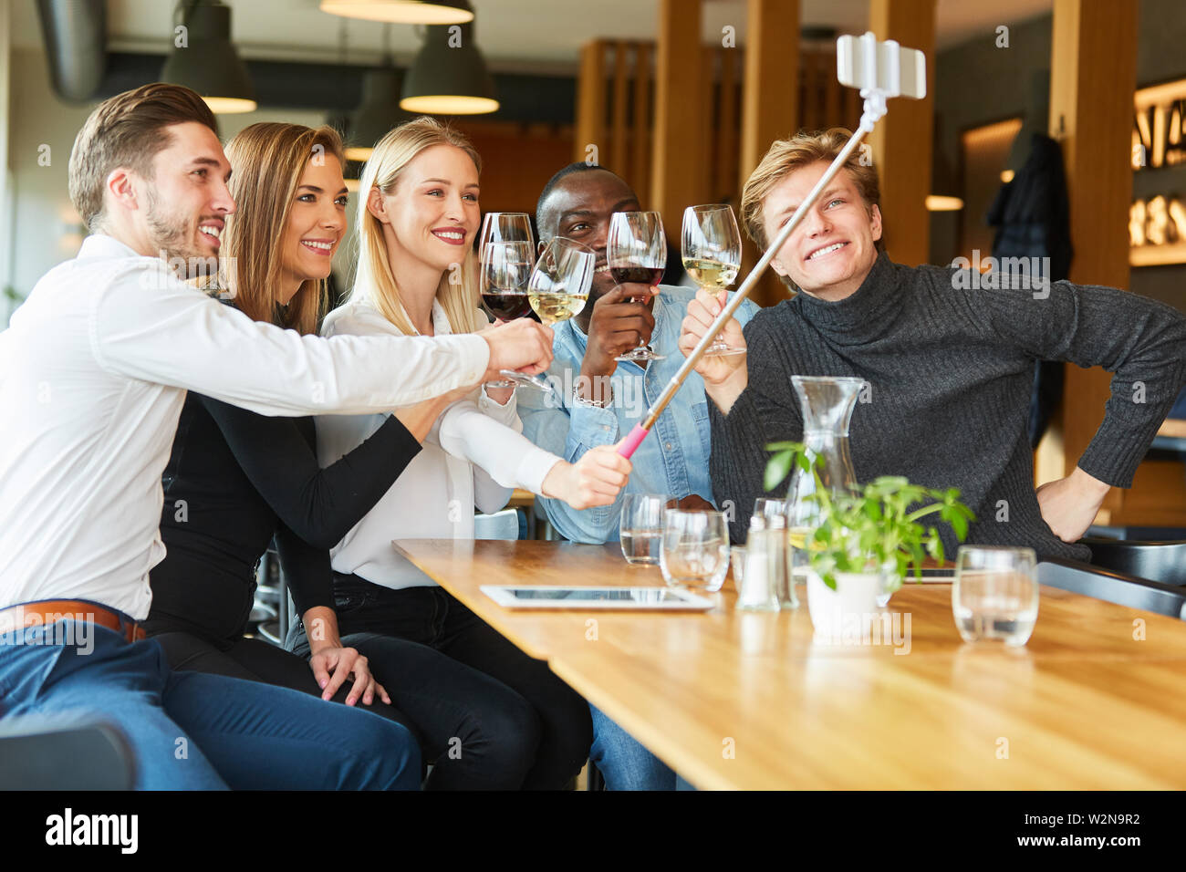 Groupe de jeunes de célébrer et de boire un vin fait dans le restaurant selfies Banque D'Images