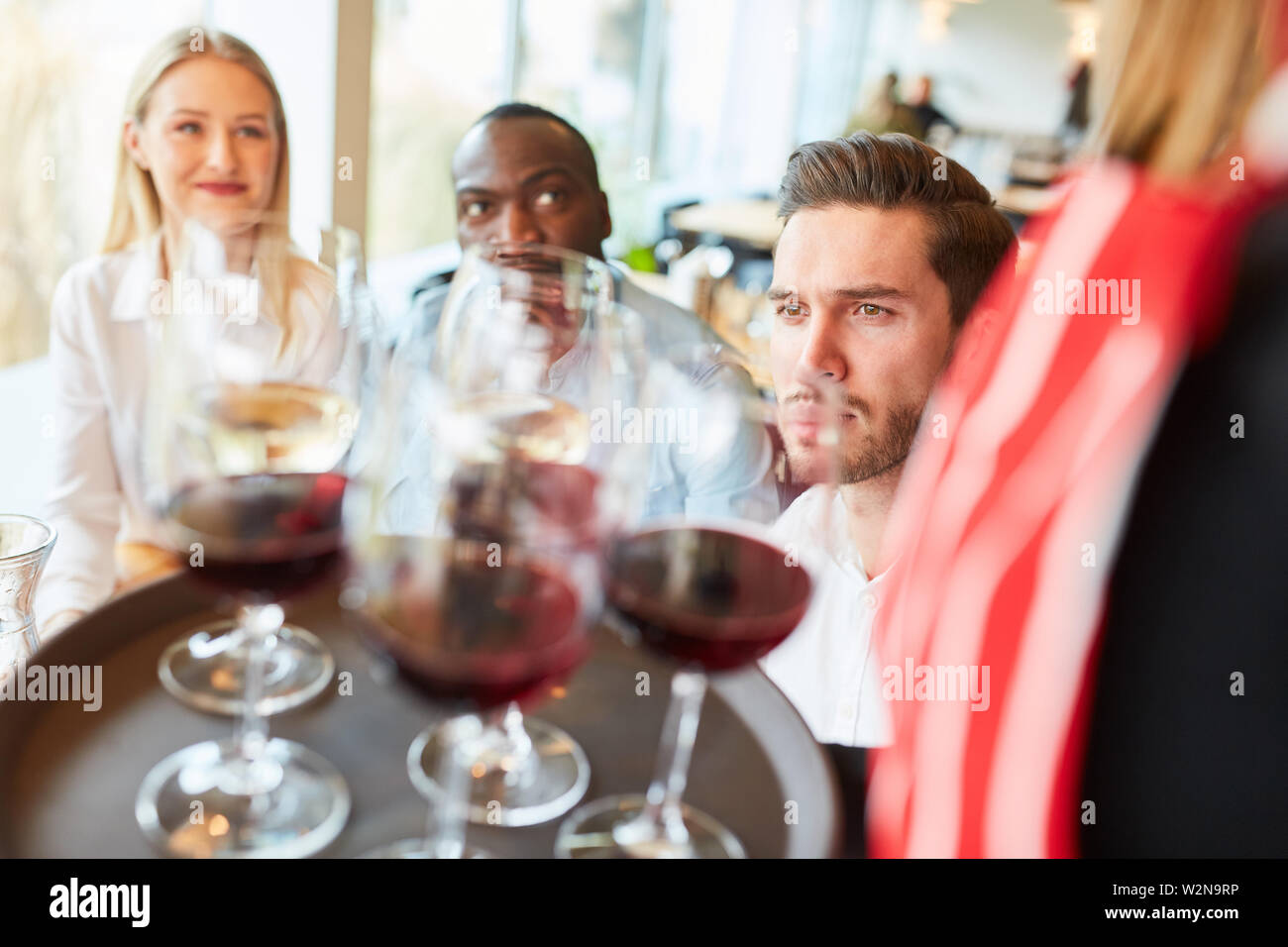 Serveuse vous sert sur un plateau avec des verres de vin rouge dans le restaurant Banque D'Images