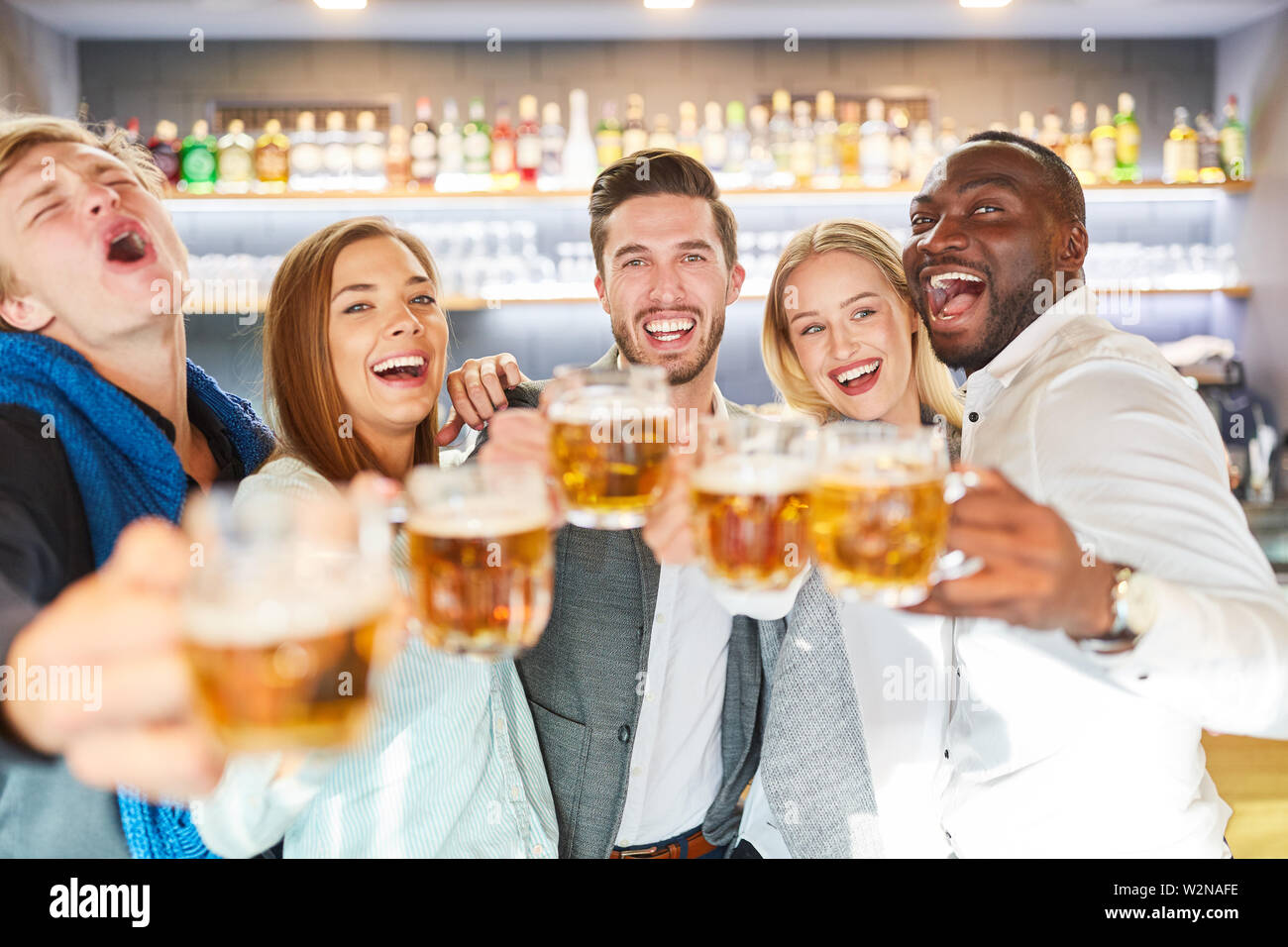 Groupe d'amis célèbre hilariously dans un pub et des toasts avec de la bière Banque D'Images