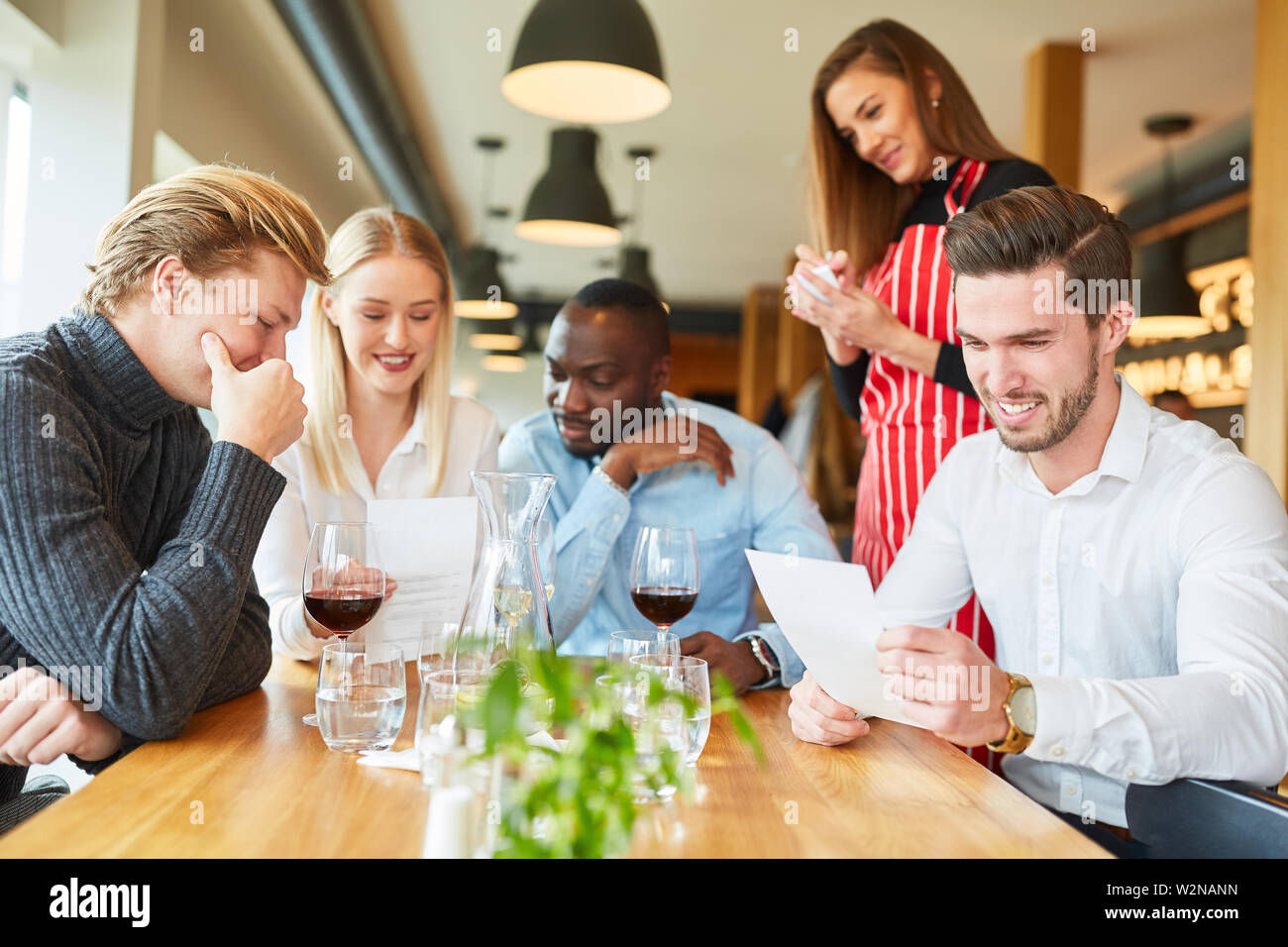 Groupe de jeunes avec menu tout en ordonnant au bistro ou restaurant Banque D'Images