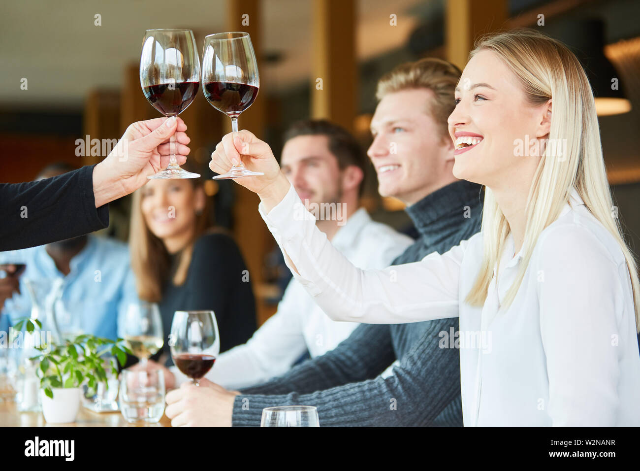 Jeune femme sur une célébration au restaurant avec des amis tout en grillage avec du vin rouge Banque D'Images