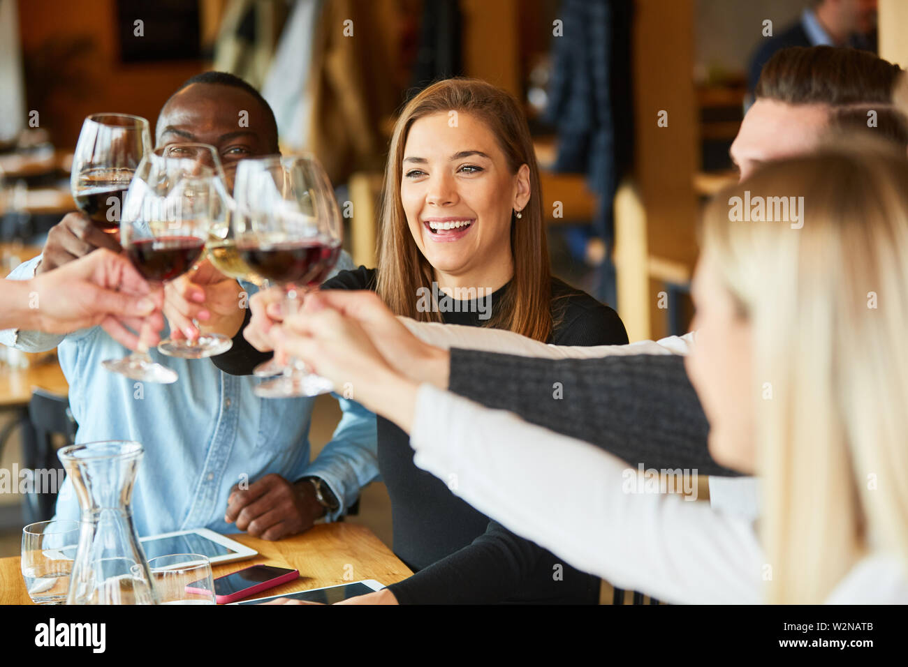 Groupe de jeunes gens fête anniversaire dans le restaurant et des toasts avec verre de vin Banque D'Images