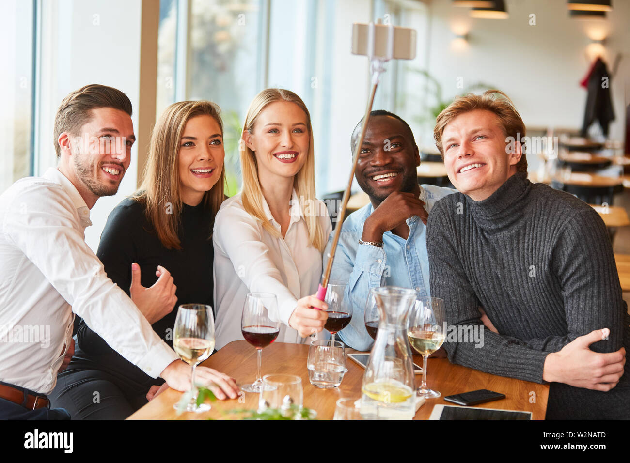 Les jeunes comme des amis dans le restaurant prendre self portrait avec le stick selfies Banque D'Images