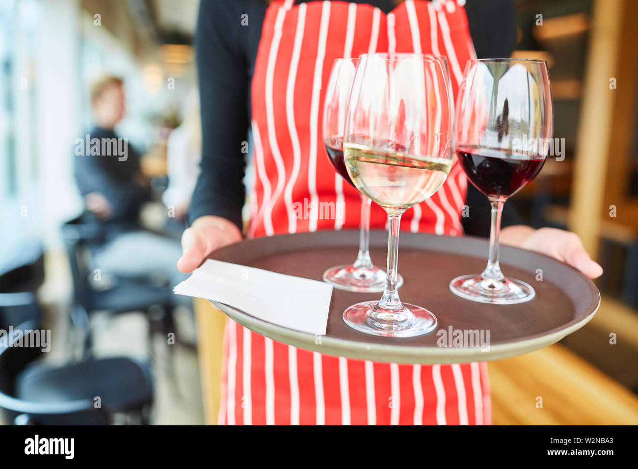 Garçon porte verres de vin sur un plateau au bistro ou restaurant Banque D'Images