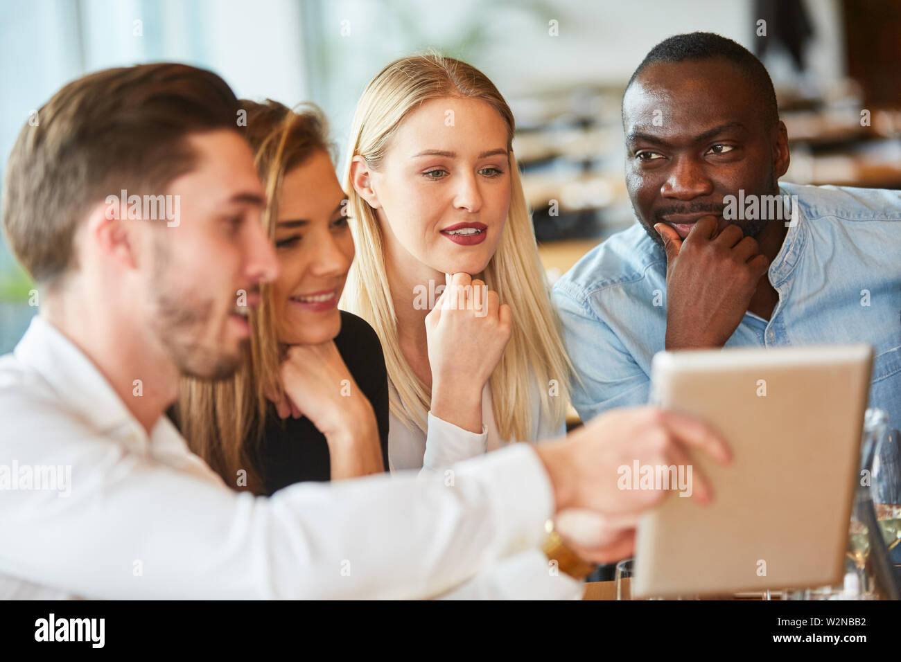 Les jeunes dans le restaurant regarder ensemble sur un ordinateur tablette Banque D'Images
