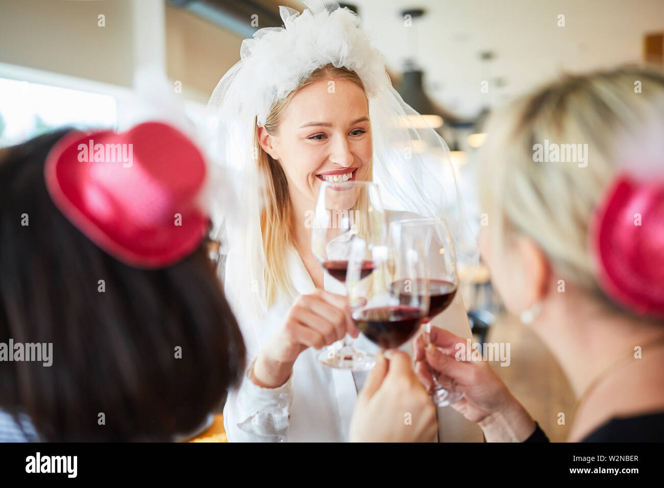 Heureuse mariée avec Bridal Veil tout en grillage avec verre de vin lors d'une fête Banque D'Images