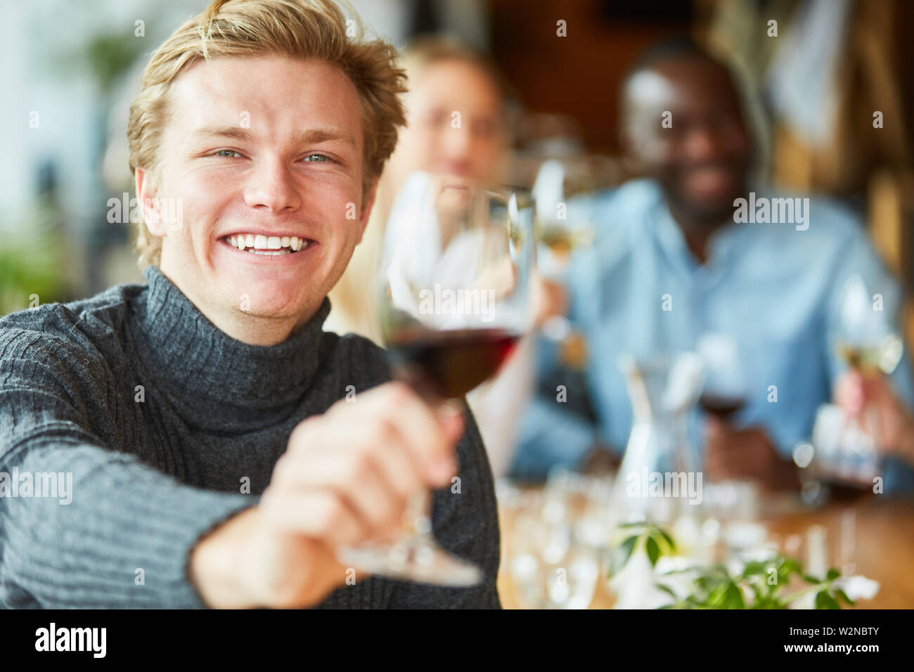 Cheerful young man dégustation avec un verre de vin rouge dans le pub Banque D'Images
