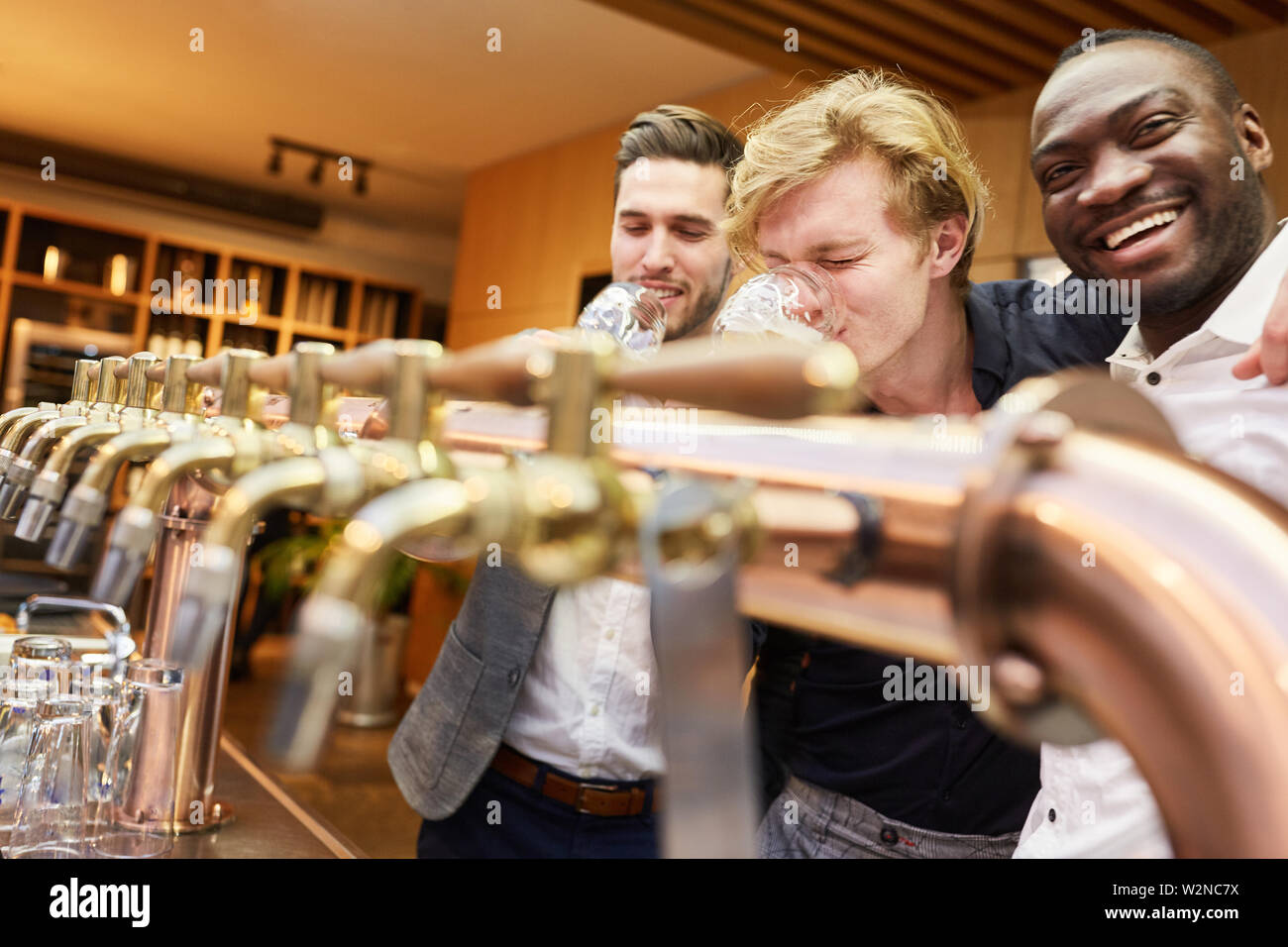 Trois hommes au guichet dans un pub boire de la bière en soirée pour hommes Banque D'Images