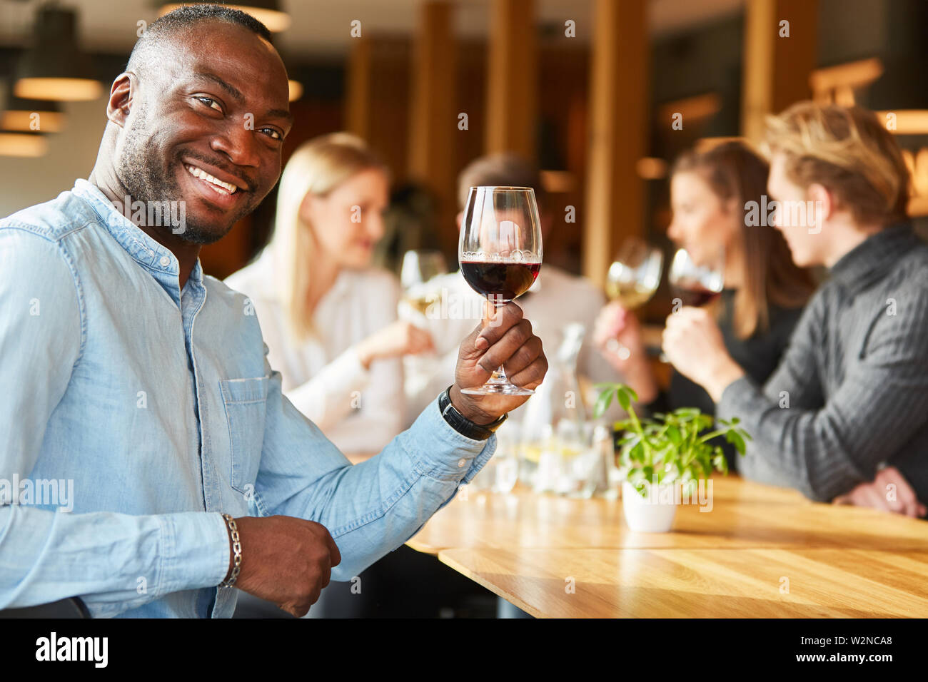 Homme africain dans le restaurant avec un verre de vin rouge dit cheers Banque D'Images