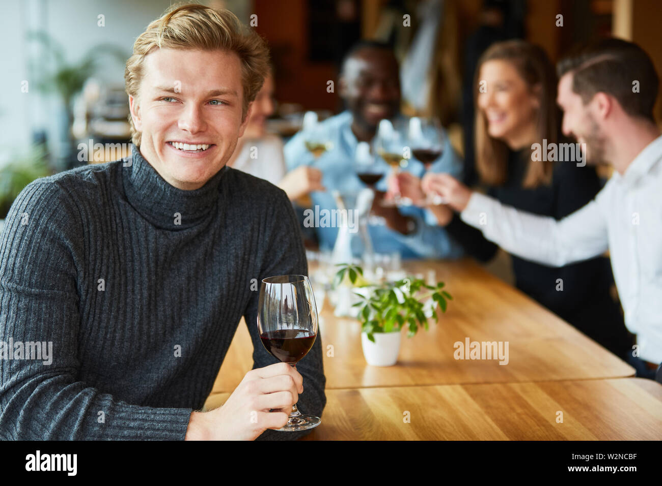 Heureux jeune homme avec un verre de vin rouge dans un restaurant ou bar Banque D'Images