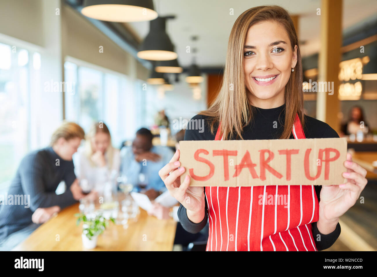 Jeune femme en tant que fondateur de restaurant avec signe dans sa start-up restauration Banque D'Images