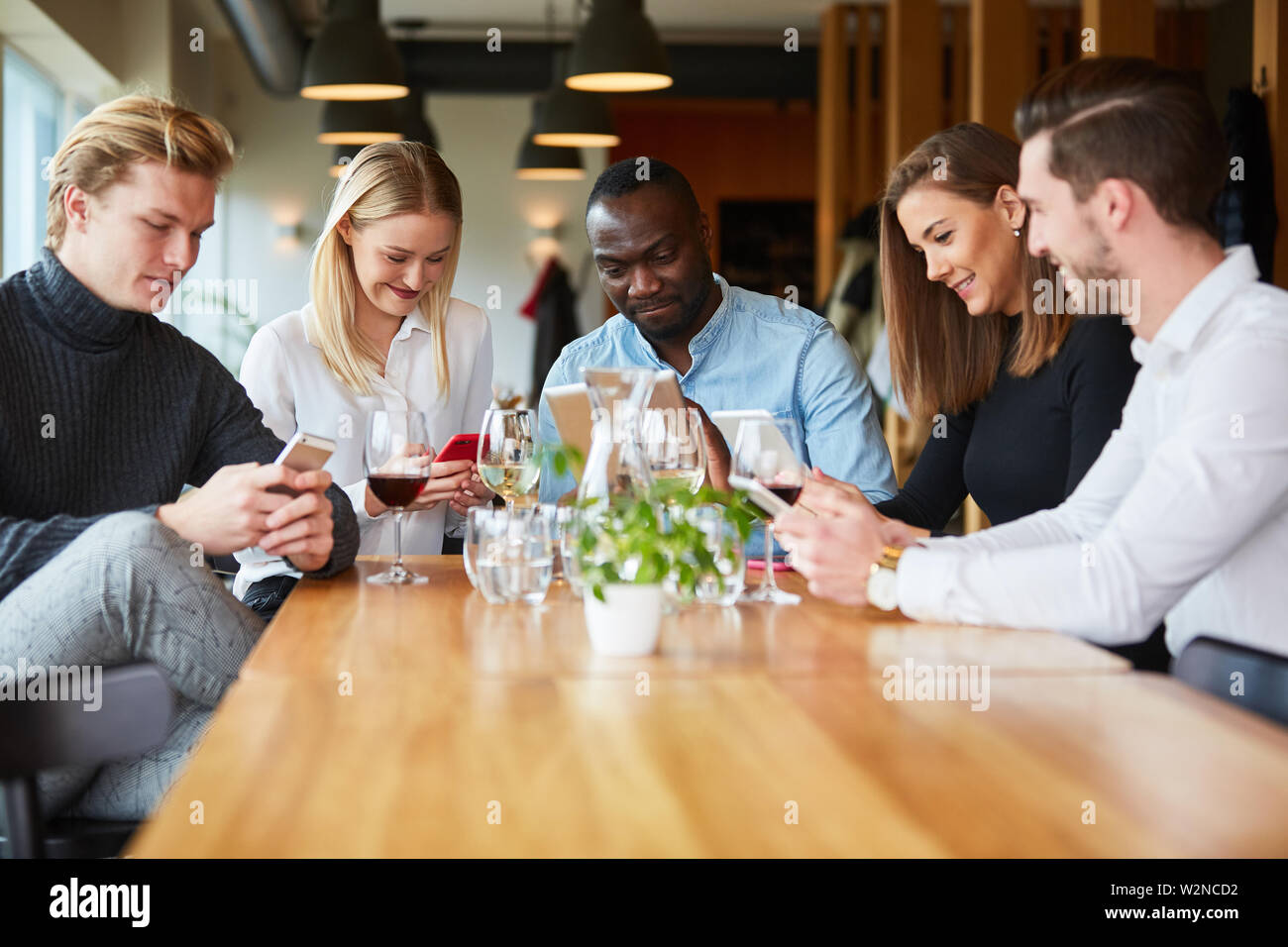 Les jeunes avec un téléphone mobile de la toxicomanie dans le restaurant regardant téléphone intelligent ou mobile Banque D'Images