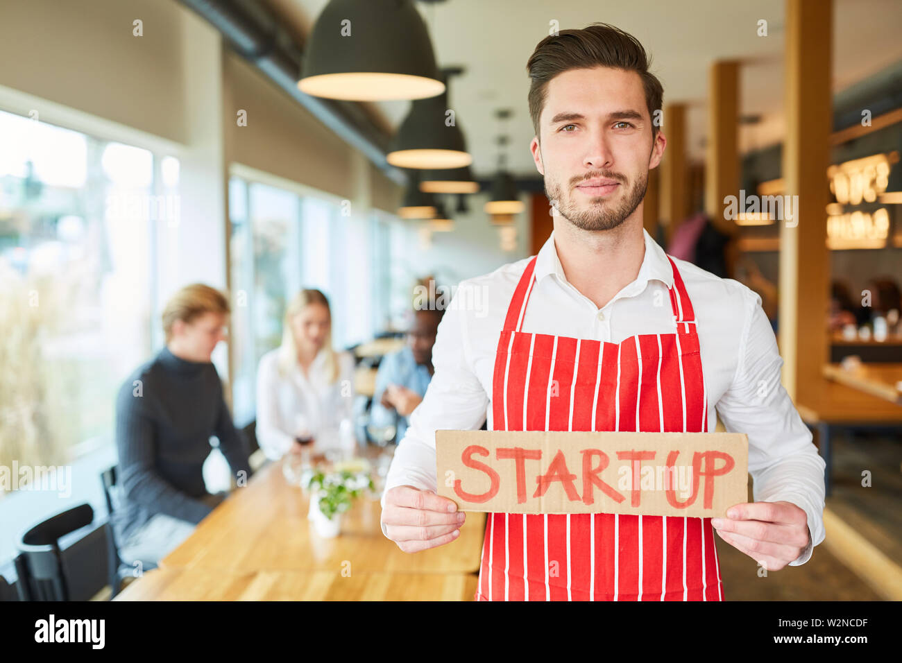 Confiante jeune serveur ou start-up fondateur avec pancarte dans le restaurant Banque D'Images