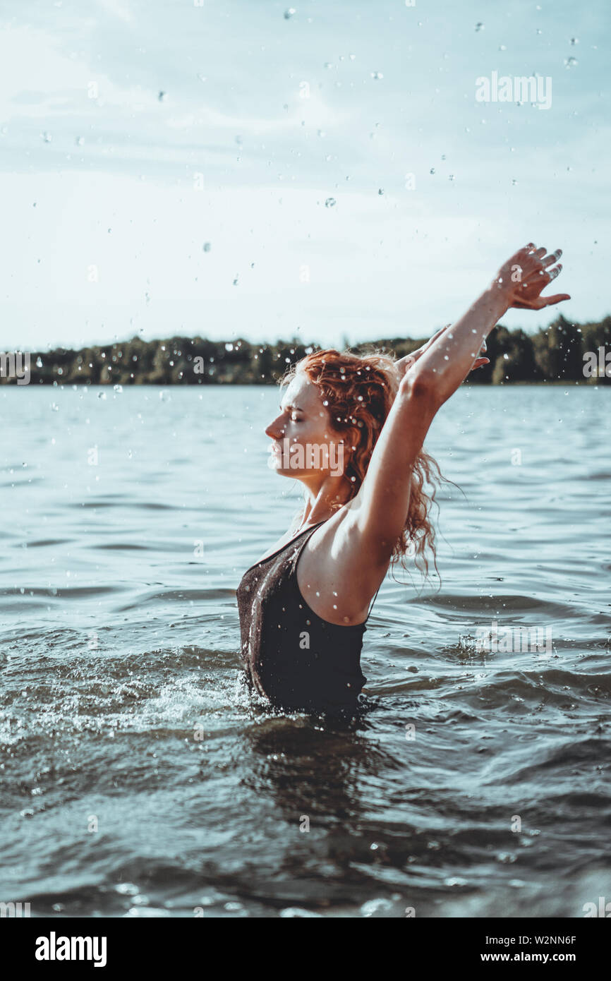 Belle Jeune femme debout dans l'eau. Maillot noir. Style vintage photo verticale. Banque D'Images