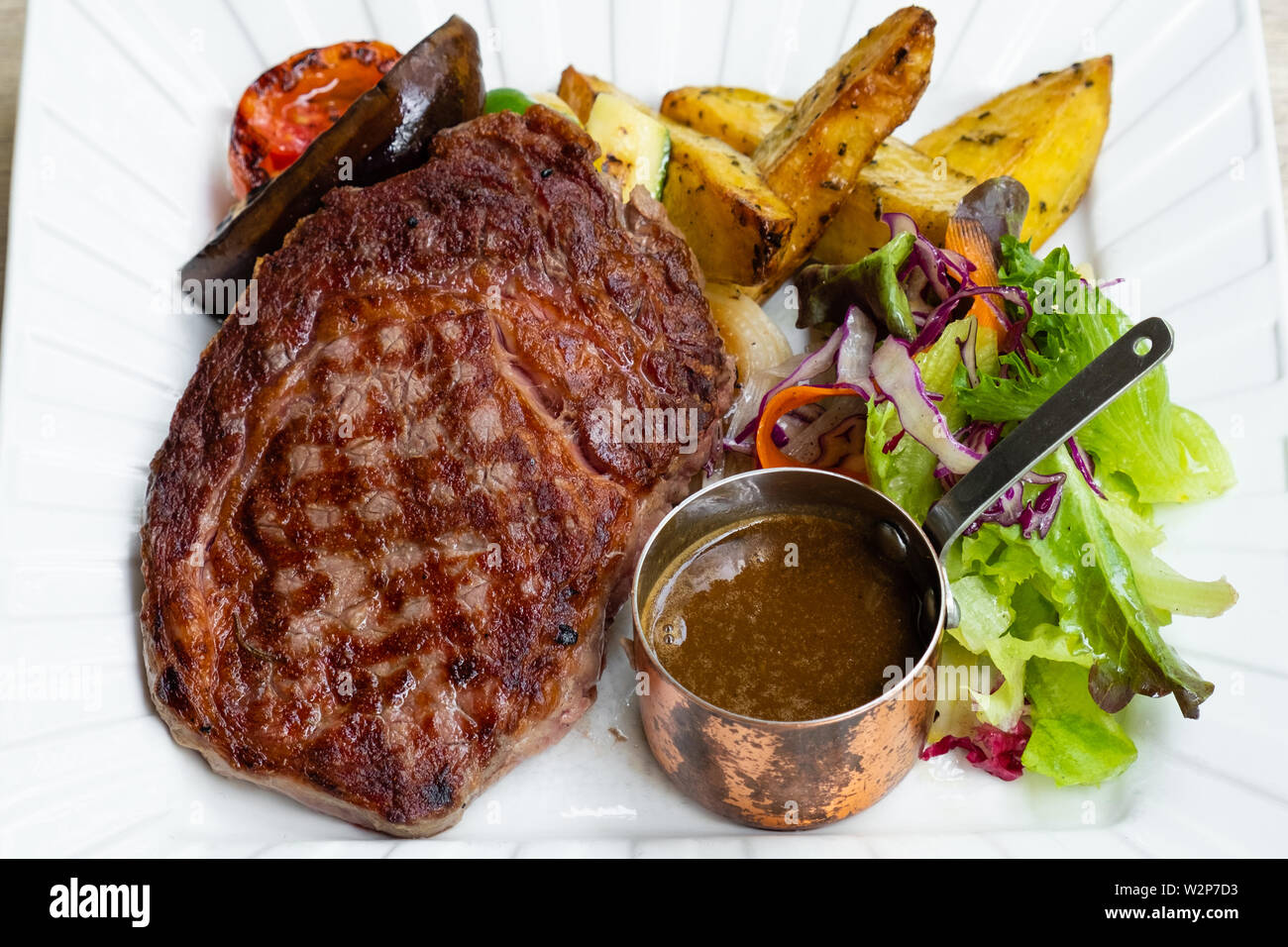 Close up de bifteck de faux-filet grillé avec légumes, pommes de terre rôties sauce fait maison barbecue , isolé dans une assiette blanche ,professional chef italien bi Banque D'Images