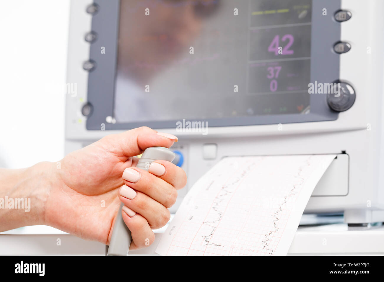 Close-up shot of pregnant woman's hand holding contrôleur de l'Cardiotocograph alias machine de monitorage électronique du foetus (EFM) enregistrement de la fetal heartb Banque D'Images