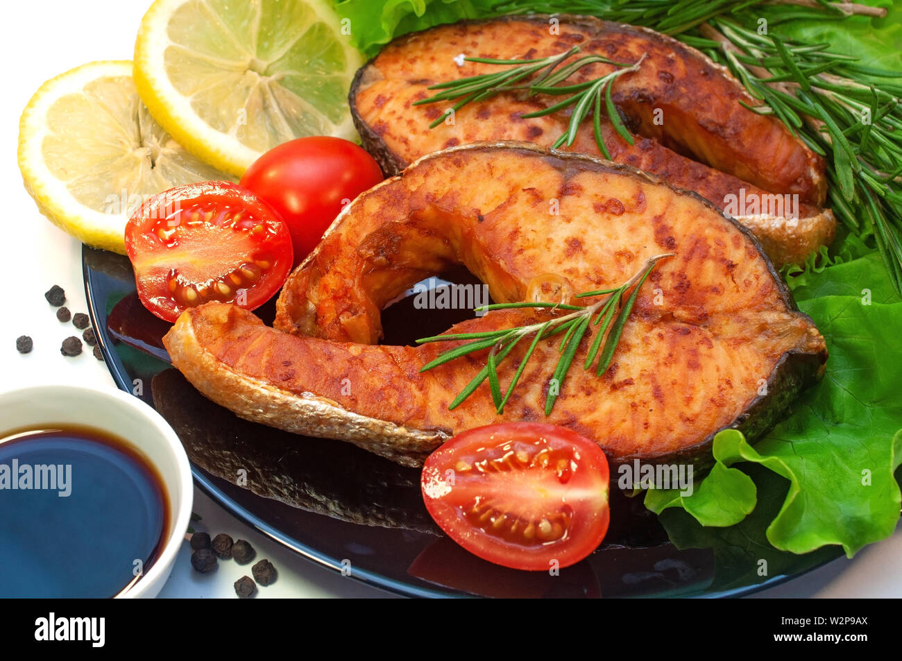 Darnes de saumon grillées sur une plaque avec du citron et tomate Banque D'Images