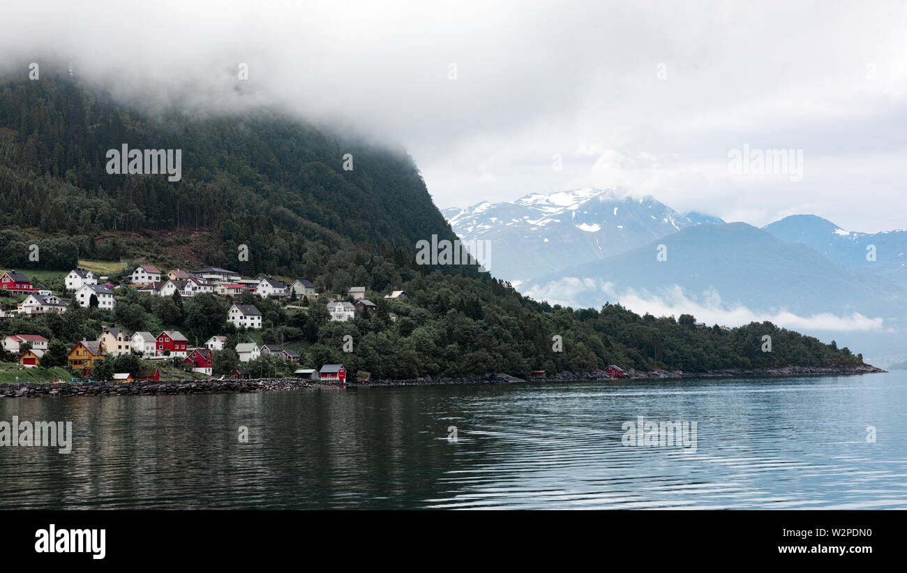 Ville de Norvège, Norvège Volda vu depuis le fjord. Mountain disparaissant dans les nuages. Arbres d'atteindre dans l'eau. Banque D'Images