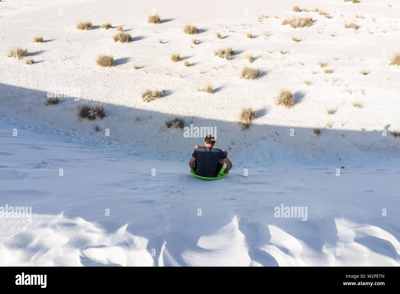 Retour de l'homme sur le sable en dunes de sable blanc national monument au Nouveau Mexique sur traîneau glissant sur disque hills Banque D'Images
