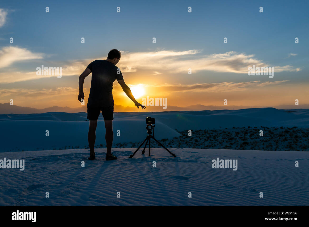 Photographe homme avec trépied faisant la photographie en accéléré avec l'appareil photo dans les dunes de sable blanc monument national en vue du Nouveau Mexique de coucher du soleil Banque D'Images