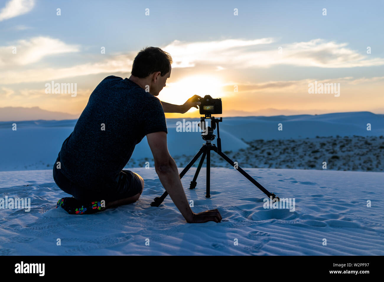 Photographe Homme assis avec trépied avec appareil photo dans les dunes de sable blanc monument national en vue du Nouveau Mexique de coucher du soleil Banque D'Images