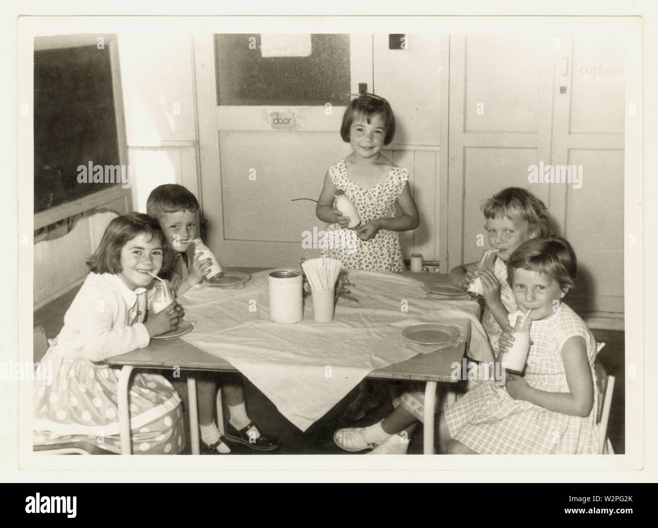 Photo originale du milieu du siècle des années 1960 d'enfants heureux de l'école primaire de boire du lait gratuit à l'école à partir d'une bouteille , peut-être Leicestershire, Royaume-Uni Banque D'Images